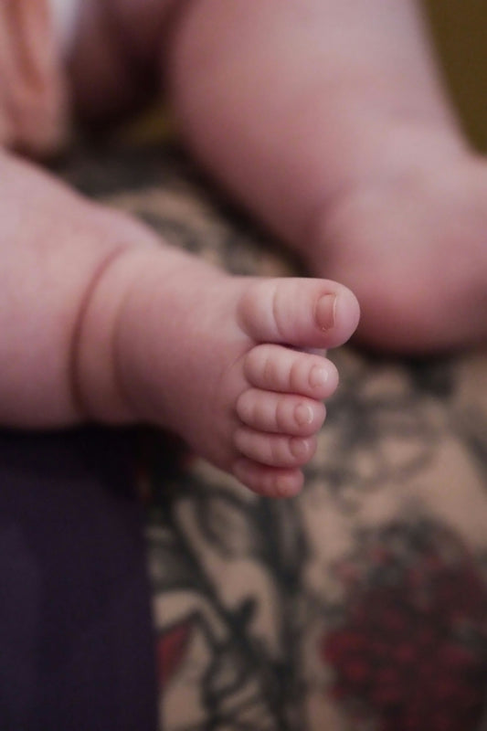 A close up of a baby's foot on a bed
